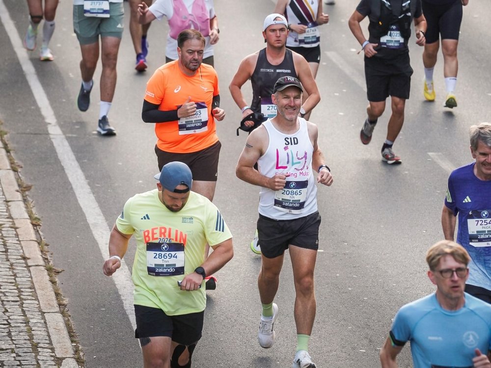 Ready for your next challenge with Team Lily? - A man in a white Lily vest running amongst other competitors in the Berlin Marathon