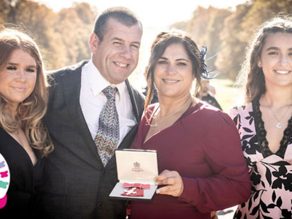 An MBE for Liz as we celebrate 15 years of fighting mito! - Lily founder Liz and her husband Dave standing together and holding Liz's MBE medal in its box with the lid open