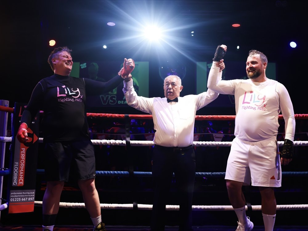 Spring into action with Team Lily! - Two boxers standing in the ring with the referee at Lily Fight Night