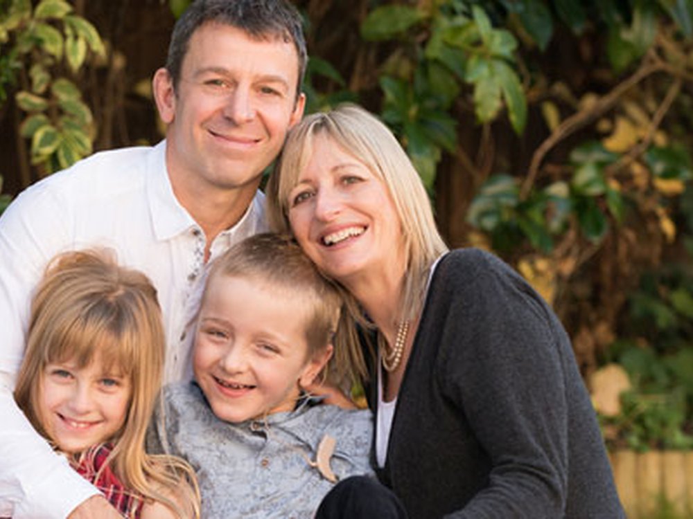 A patient-powered approach to fighting mito - A man, lady and two children huddled together in the garden smiling