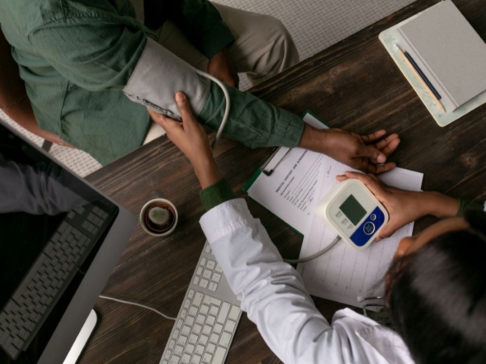 Overhead of a medical professional taking the blood pressure of a patient at a desk