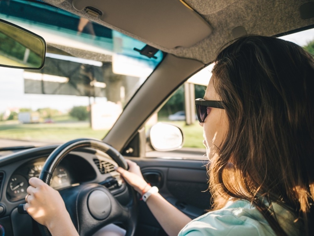 Close-up of a woman with long dark hair at the steering wheel of a car