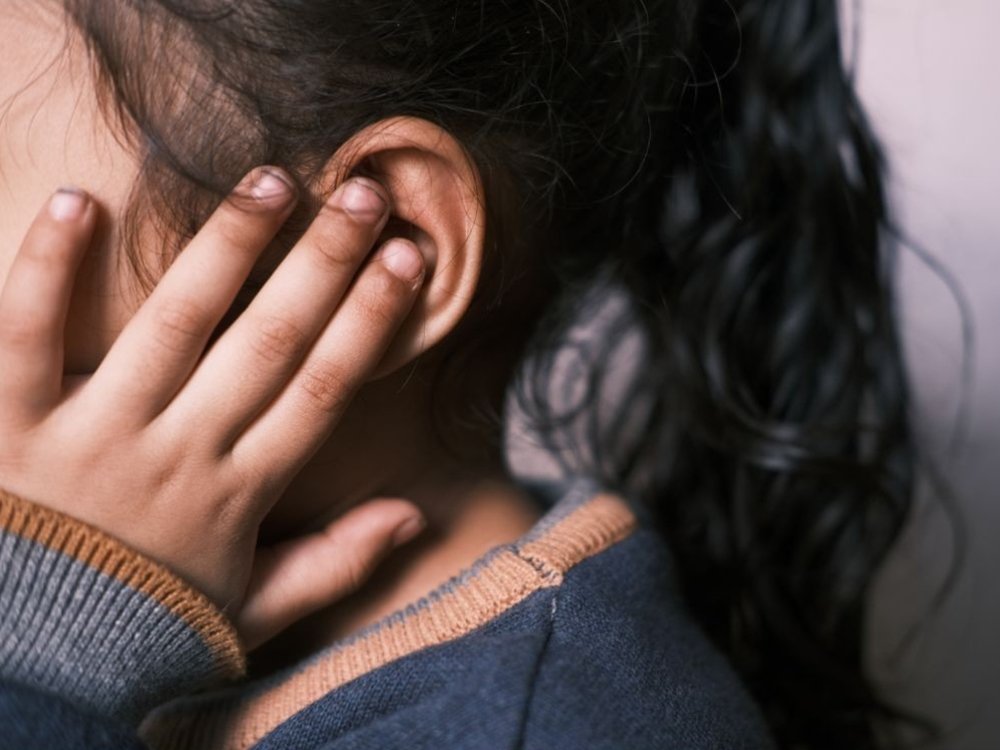 Close-up of a young girl with her hand over her left ear