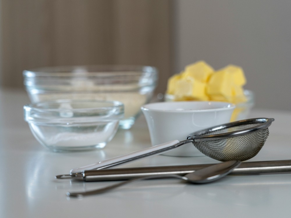 Silver and black kitchen utensils on surface with glass bowls