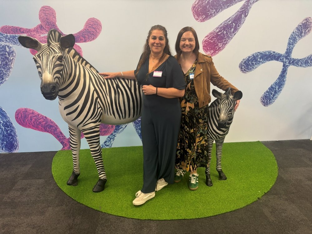 The Lily Foundation's Liz and Katie standing next to a large plastic zebra at a conference