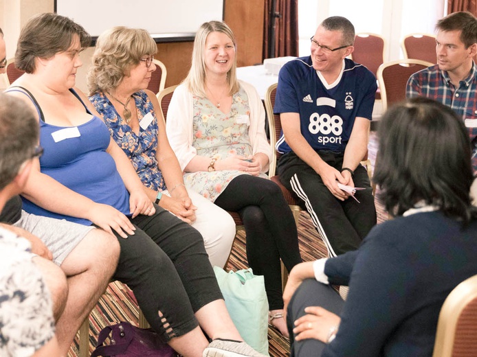 A group of mitochondrial disease patients sat on chairs in a circle talking to each other