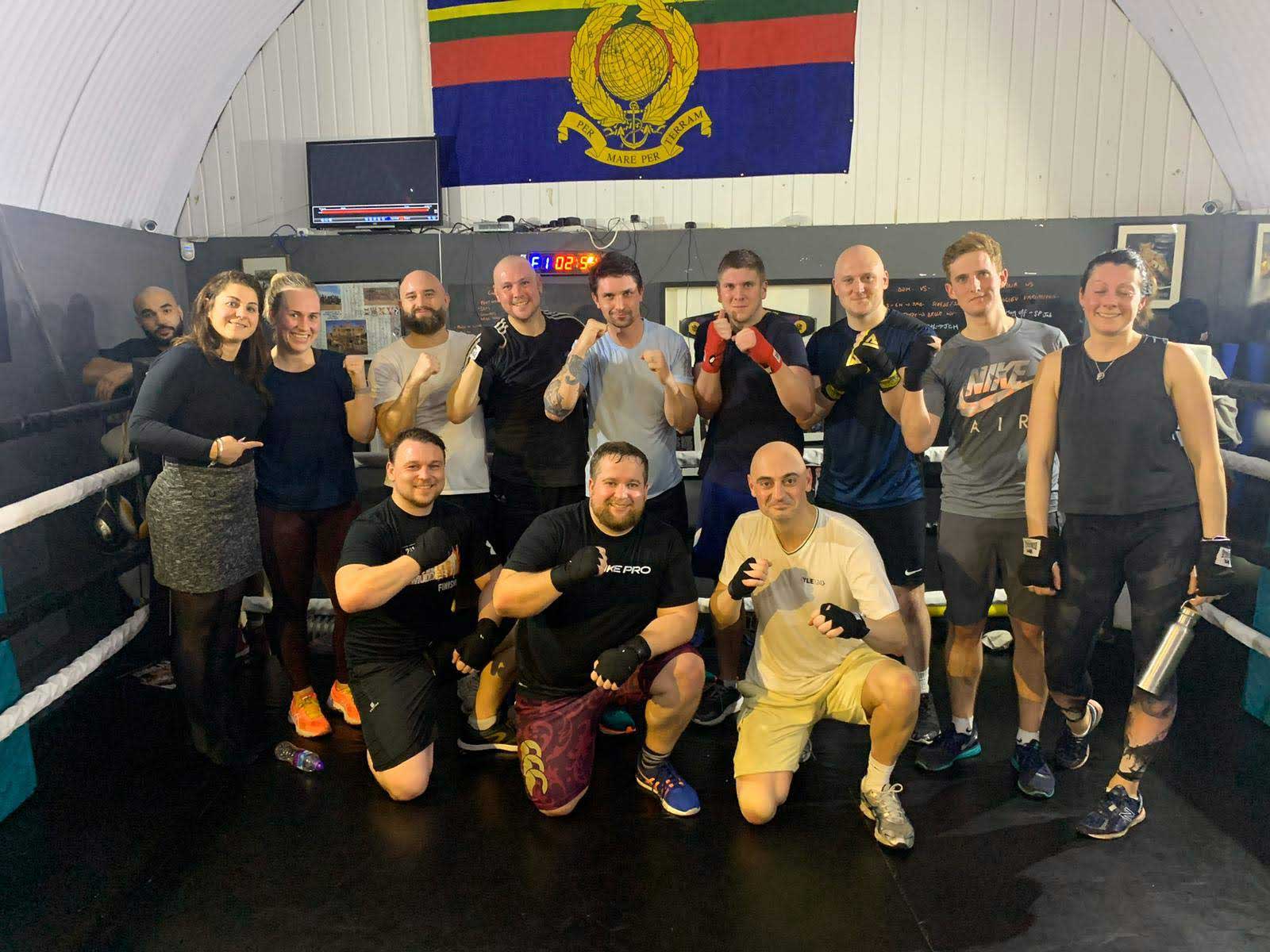 A group of men and women in a boxing ring holding their fists up