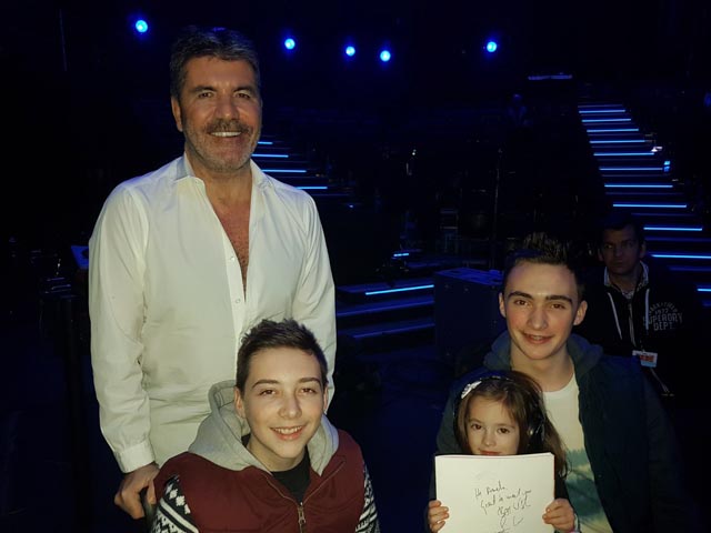 Simon Cowell stands next to a boy in a wheel chair